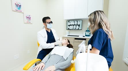 The reception at Dream Smile Dental in Rego Park, with yellow chairs and a curved white desk