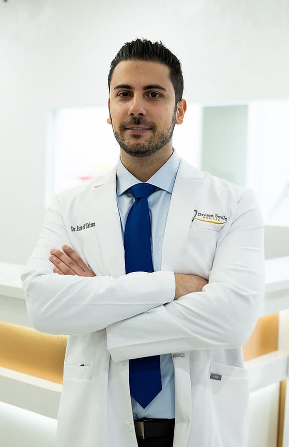 Dr. Israel Shimunov in a white coat and blue tie, arms crossed, in the Dream Smile Dental office